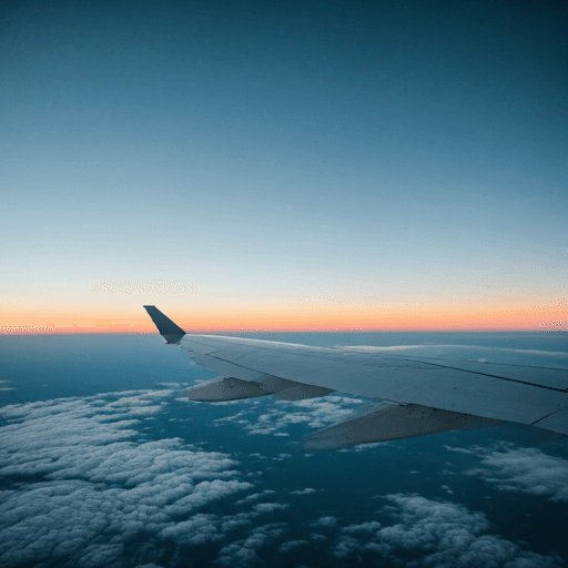 Modern jet wing view above sunset clouds
